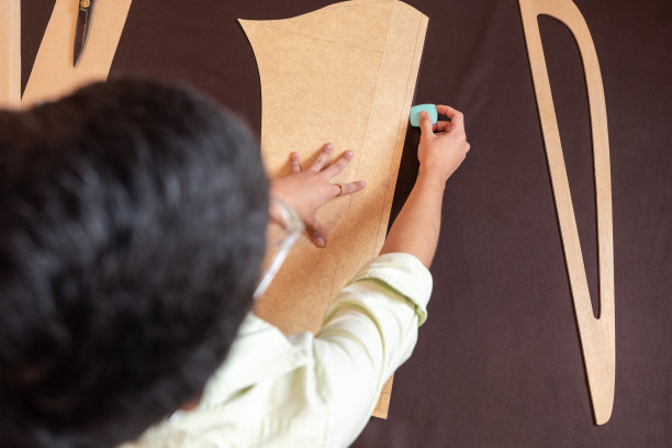 一个女人在工作室里给一件衣服做裁剪的俯视图图片下载