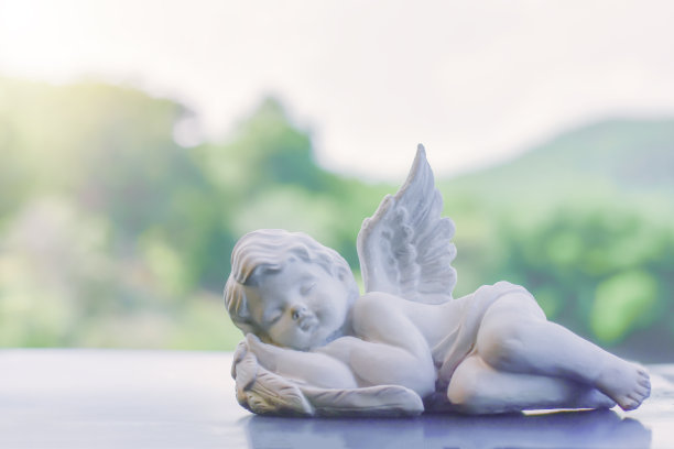一个小丘比特的陶瓷娃娃睡在木地板上。用于家庭、花园和室内外安装和装饰咖啡馆的物品图片下载