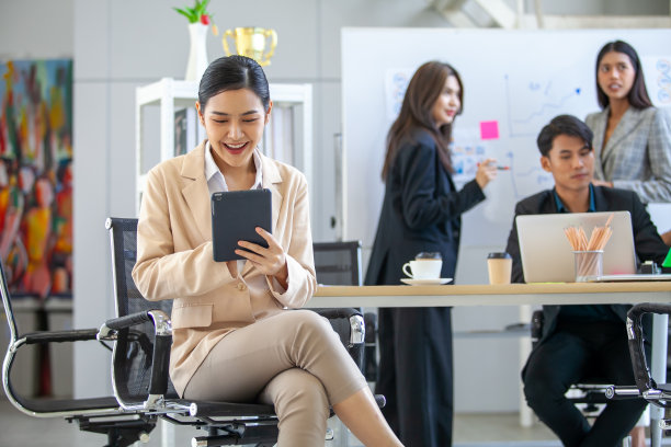 亚洲美丽的商业女性在办公室工作的肖像，美丽的女性在工作场所使用触摸板微笑。图片下载