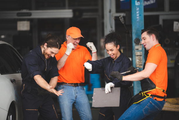 一群穿着制服的男女修车工在车库里享受和庆祝，女工人拿着剪板图片下载