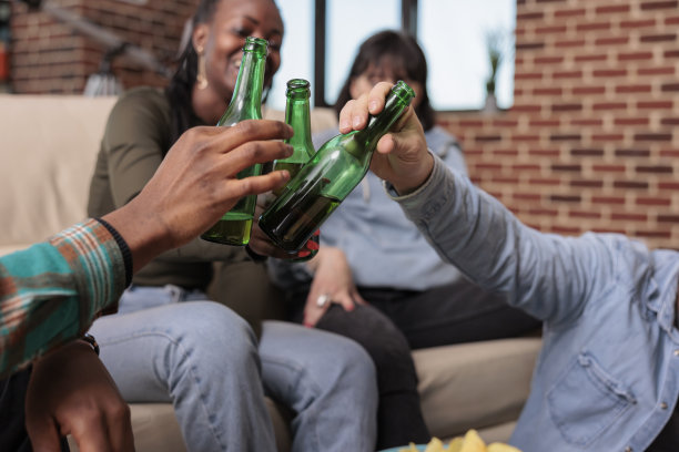 多民族的朋友在家里碰杯喝啤酒图片下载
