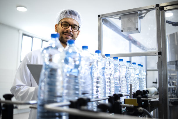 在装瓶厂有经验的白色无菌服检验非碳酸水纯度和质量控制技术员。图片下载