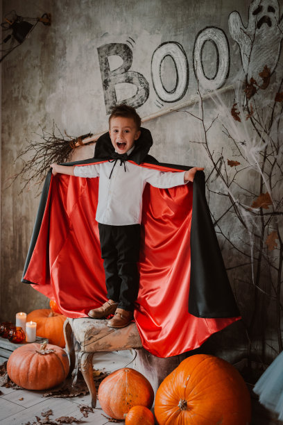 万圣节，一个穿着吸血鬼服装的男孩站在南瓜中间。图片下载