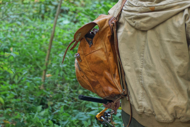 一个穿着灰色夹克的男子背着棕色的皮制双肩包旋转着图片下载