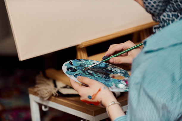 一名戴着头巾的妇女用画笔和蛋彩画在画布上作画图片下载