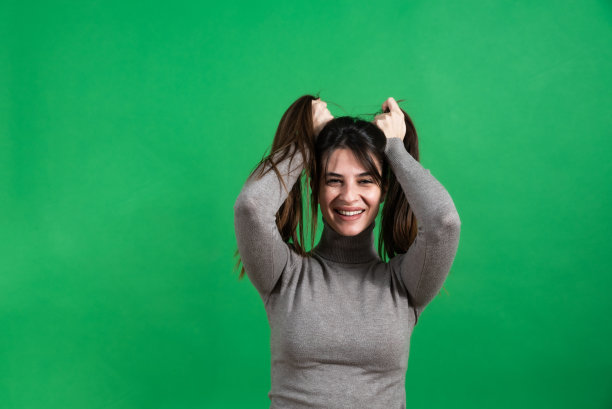 年轻美丽的女人或女孩模型在绿色屏幕背景前摆姿势。女性肖像与色度关键背景。图片下载
