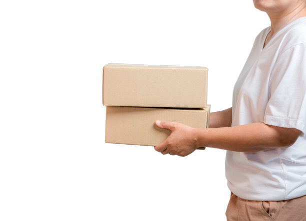 一个包裹纸板包裹盒在一个快递员的手孤立在白色背景。送货服务的概念。拿着包裹的年轻女孩是一个快递商。图片下载