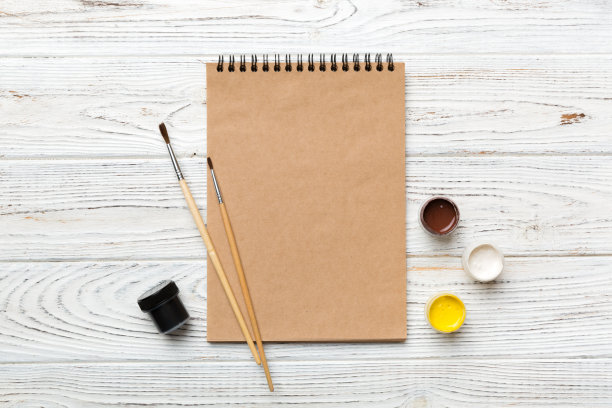 画册的页面和颜料，铅笔，刷子在彩色背景上。空白处的俯视图。工作场所的创造力。家庭教学概念图图片下载