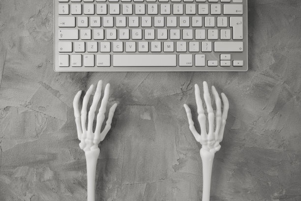 万圣节灰色背景骷髅手和电脑键盘。网上购物横幅模型图片下载