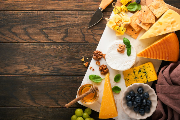 奶酪，蜂蜜，饼干，蓝莓，葡萄与红葡萄酒和白葡萄酒在玻璃杯开胃菜服务器在白色大理石板上旧的乡村木桌背景。平铺，复制空间。图片下载