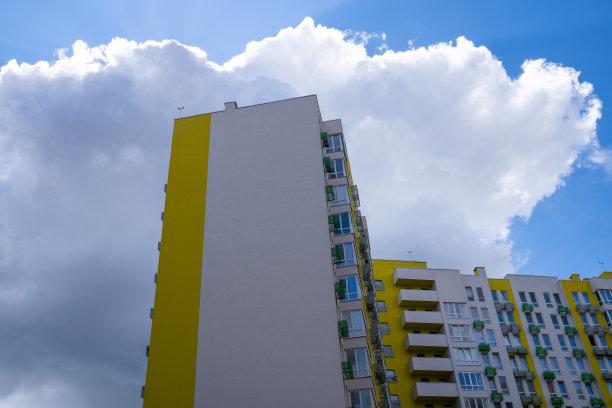 现代的城市建筑，巨大的灰色乌云笼罩着居民楼，即将下雨，沉闷的天气，明亮的家庭综合体在城市图片下载