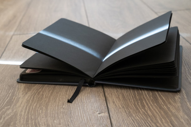 在木制背景上打开课本，黑色的书页，创造阳光光线的效果线条。咒语书的魔法食谱，童话。黑魔法的女巫配件。阅读的过程图片下载