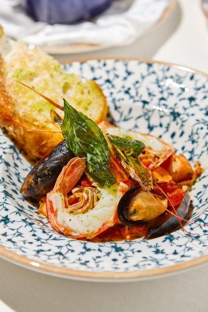 海鲜拼盘与熟虾，贻贝，海扇贝在番茄酱白色桌子。用意大利风味的夏巴塔面包炖海鲜。海鲜菜:陶瓷盘上的大虾、贝类、扇贝。图片下载
