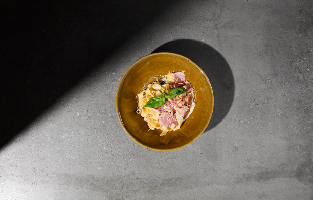 意大利干酪意面配培根和奶油酱。意大利宽面条在陶瓷盘子上的灰色桌子硬阴影。意大利宽面条加意大利干酪酱，背景是灰色的石头和阴影。图片下载