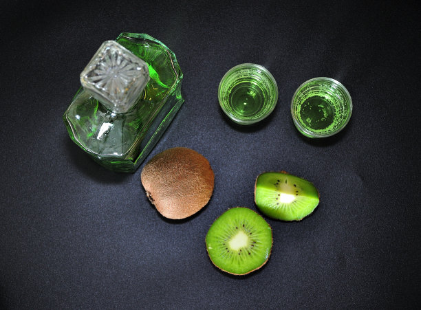 猕猴桃利口酒、成熟的热带水果和一瓶黑色背景的酒精饮料。图片下载