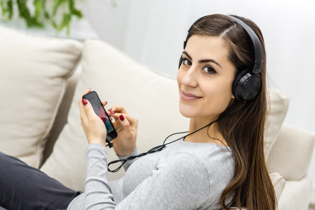 腹部戴着耳机的孕妇的侧面照片。图片下载