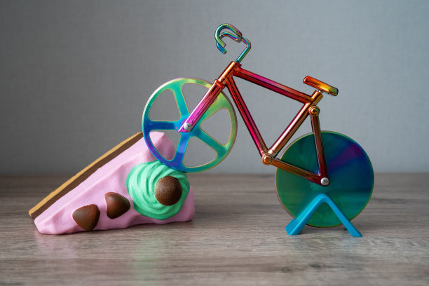 五颜六色的剪刀在形状自行车上鲜艳的一块海绵蛋糕，切蛋糕，创意照片艺术，生日明信片，健康的生活方式，饮食图片下载