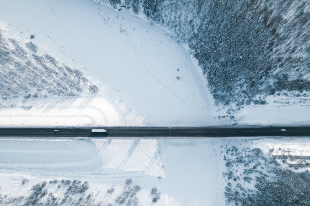 一辆带着拖车的大卡车和几辆汽车停在冬天横跨河的桥上图片下载