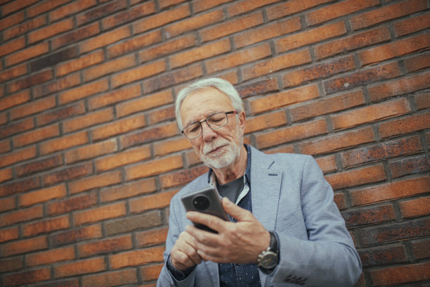 一位资深商人正在用手机打短信。图片下载