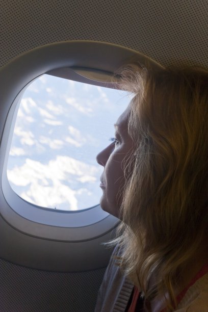 在她的飞行中，金发女人看着窗外图片下载