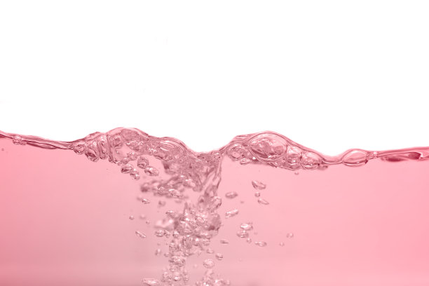 水飞溅，波纹和气泡运动在粉红色的光背景。图片下载