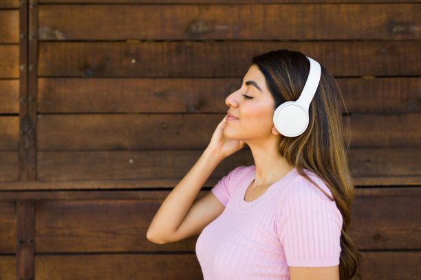 年轻的拉丁女子戴着耳机放松地听音乐图片下载