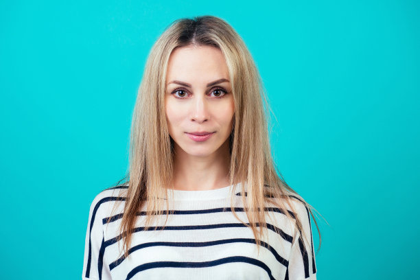 肖像迷人的女人短发和化妆微笑在工作室的蓝色背景。图片下载