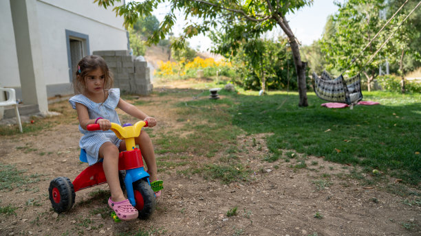女孩在后院骑三轮车照片图片下载