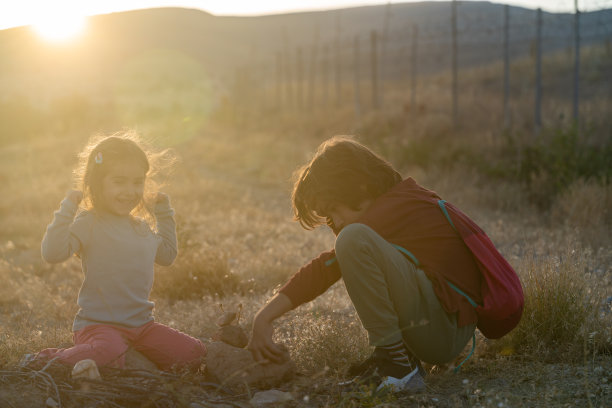 兄妹在户外玩小石头的照片图片下载