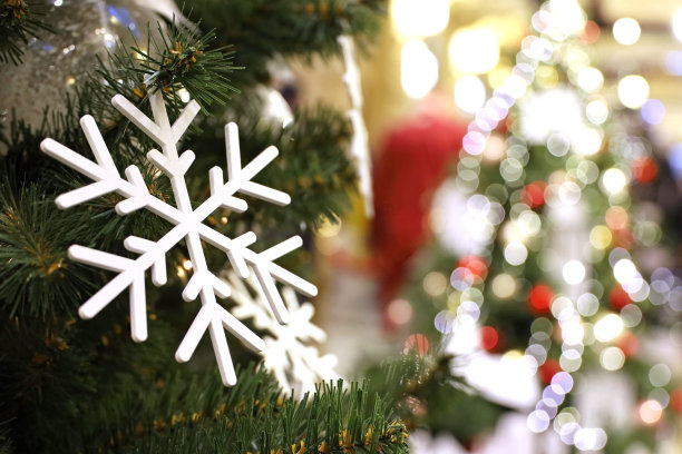 购物中心的圣诞树上有玩具雪花，背景是模糊的节日彩灯图片下载