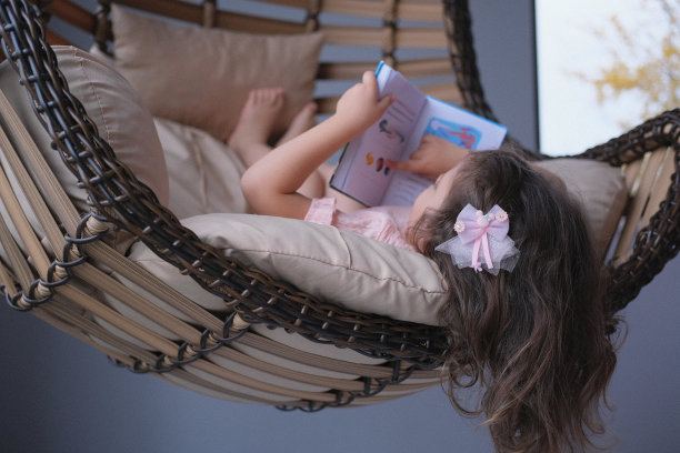 一个可爱的小女孩正在荡秋千看书图片下载