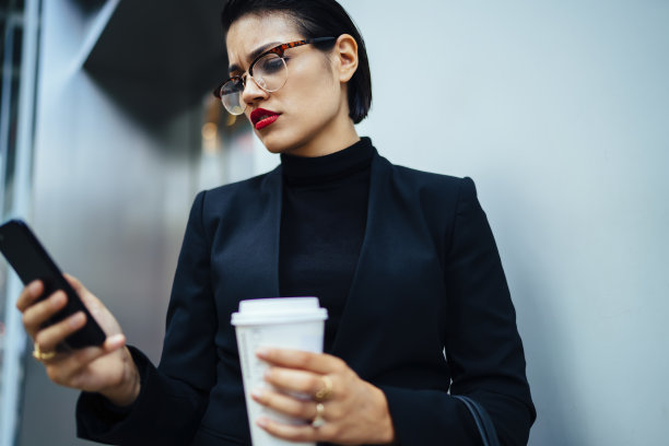 专注于穿正装的女性在智能手机上发信息图片下载