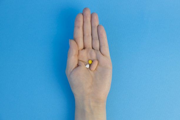 心形的药丸躺在手掌上。在蓝色背景上。从以上观点。图片下载