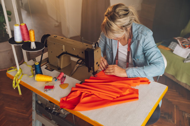 一名裁缝坐在工作室的缝纫机上做针线活图片下载