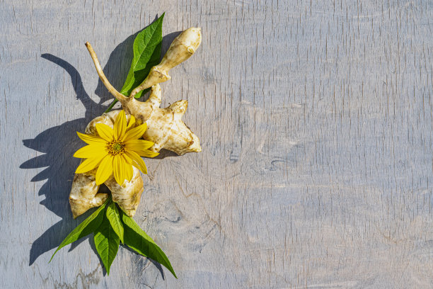 耶路撒冷洋蓟蔬菜根，黄花绿叶放在一张旧木桌上，俯视图。图片下载