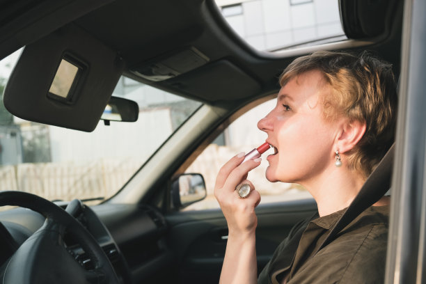 开车的短发中年妇女在嘴唇上涂了口红图片下载