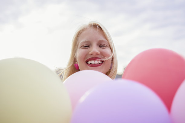 透过五颜六色的气球，开心地看着镜头!图片下载