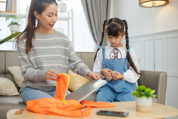 亚洲母亲帮助女儿背着书包准备上学。图片下载
