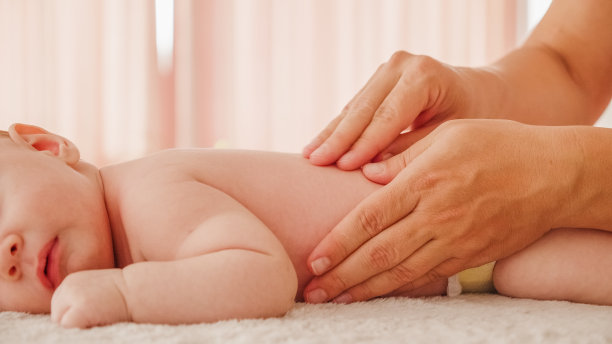 母亲正在给她健康的婴儿按摩。白人新生儿趴在地上，他的母亲正在为他的小后背和正在发育的肌肉做按摩。图片下载