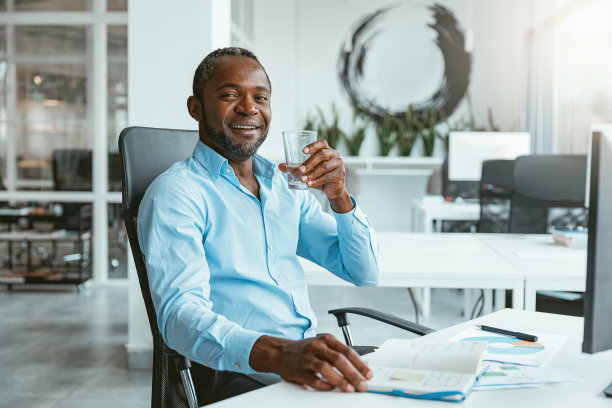 非洲商人在电脑前工作，坐在现代化的办公室里喝水图片下载
