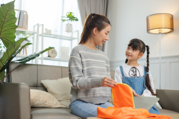 亚洲母亲帮助女儿背着书包准备上学。图片下载