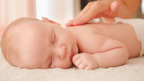 母亲正在给她健康熟睡的婴儿按摩。小白种新生儿躺在他的肚子上休息，而他的母亲正在为他的小背部和发展中的肌肉进行按摩。图片下载