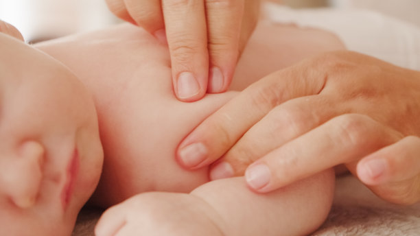 母亲正在给她健康熟睡的婴儿按摩。小白种新生儿躺在他的肚子上休息，而他的母亲正在为他的小背部和发展中的肌肉进行按摩。图片下载