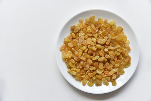 黄色多汁葡萄干放在白色盘子里图片下载