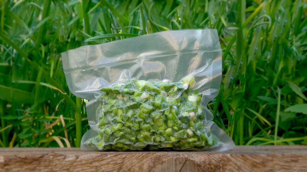 脱气器产品。一个密封的袋子里的绿色植物矗立在一个木质表面上，背景是绿色的草。为冬天做准备。保护。图片下载