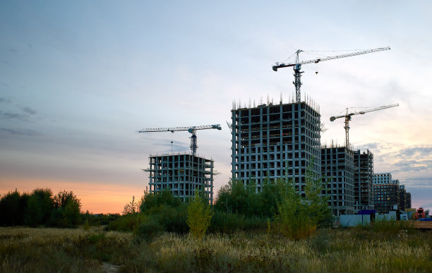 日落时分，建筑工地上正在施工的塔吊和高层建筑的黑色剪影图片下载