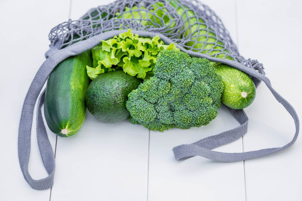 白色木制背景上的绿色蔬菜特写串线袋。健康的膳食食品。健康营养、素食和生态的概念。拒绝使用塑料袋。图片下载