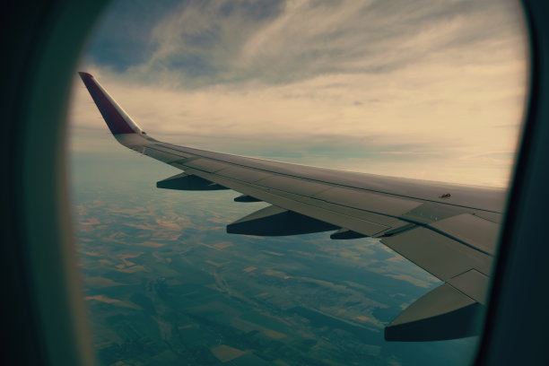 飞机窗口的照片，美丽的田野和一些蓬松的云。图片下载