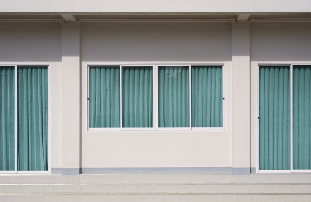 米色办公楼内的玻璃滑动门和窗户的正面与蓝色窗帘图片下载