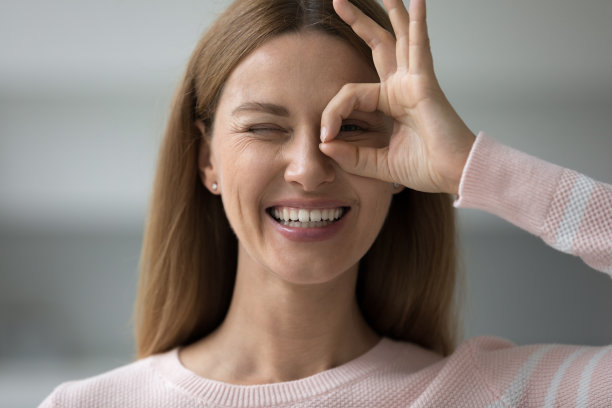 快乐的成年妇女通过手手指双筒望远镜看着相机图片下载